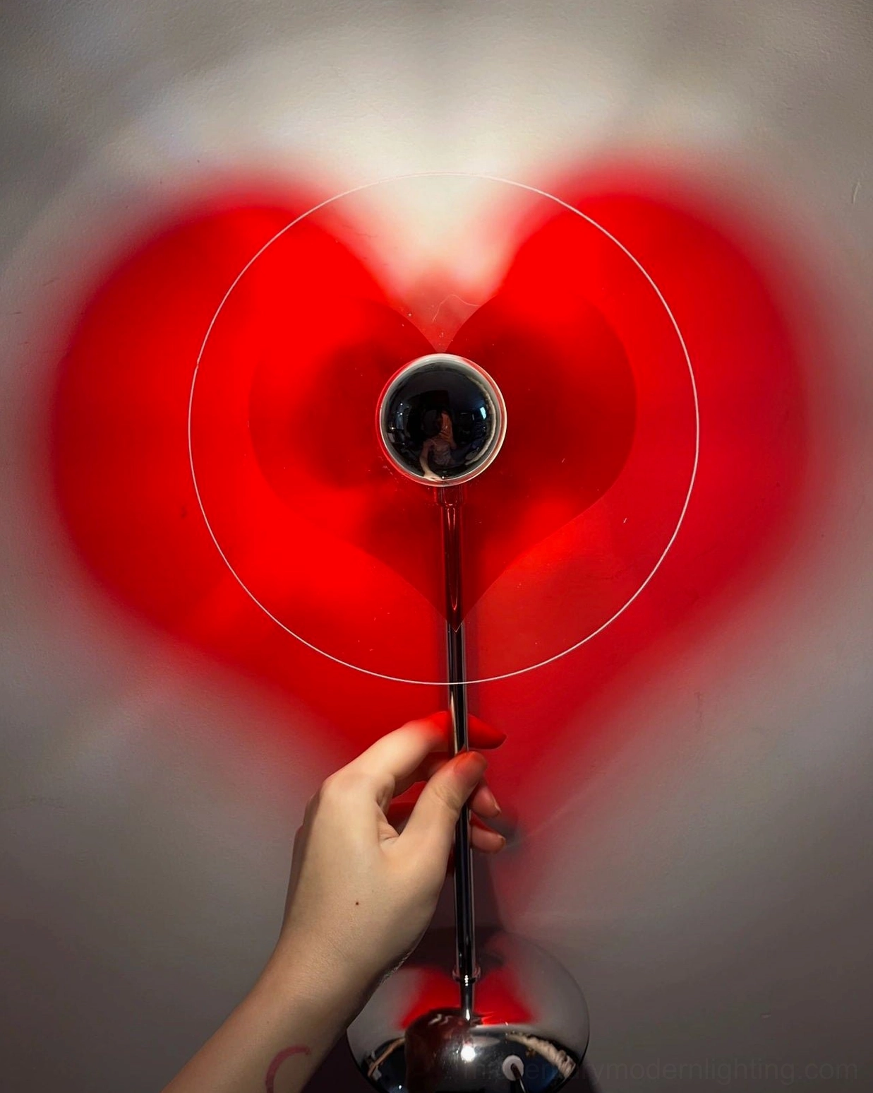 Close-up front view of handheld heart projection lamp showing circular light ring and glowing red heart shadow effect