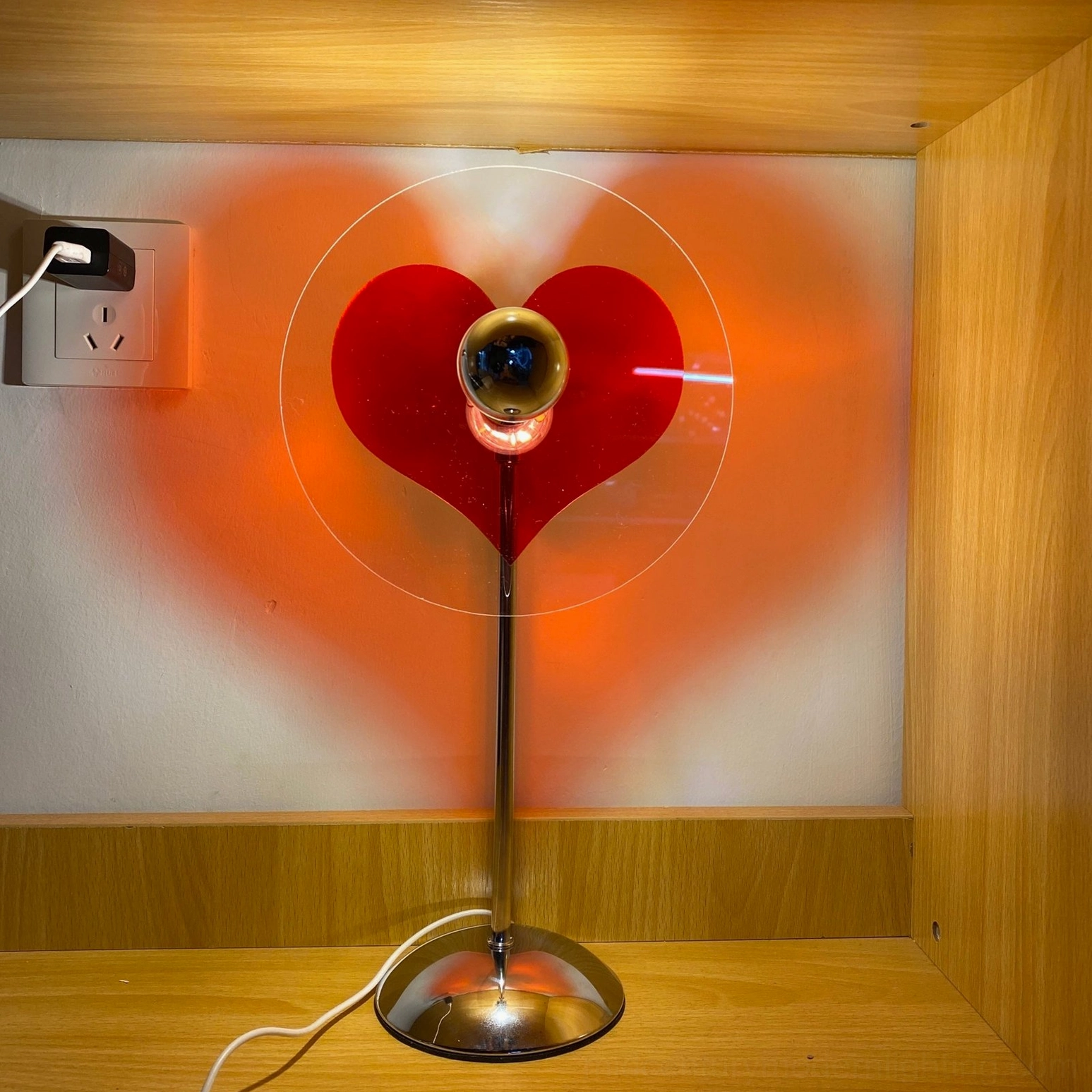 Heart projection lamp casting clear heart silhouette, modern minimalist design on desk surface
