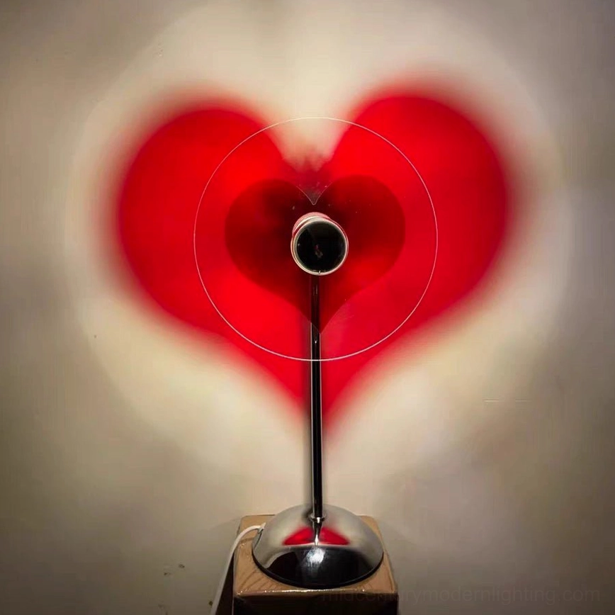 Red heart shadow projection cast by LED table lamp on white wall, romantic ambient lighting effect