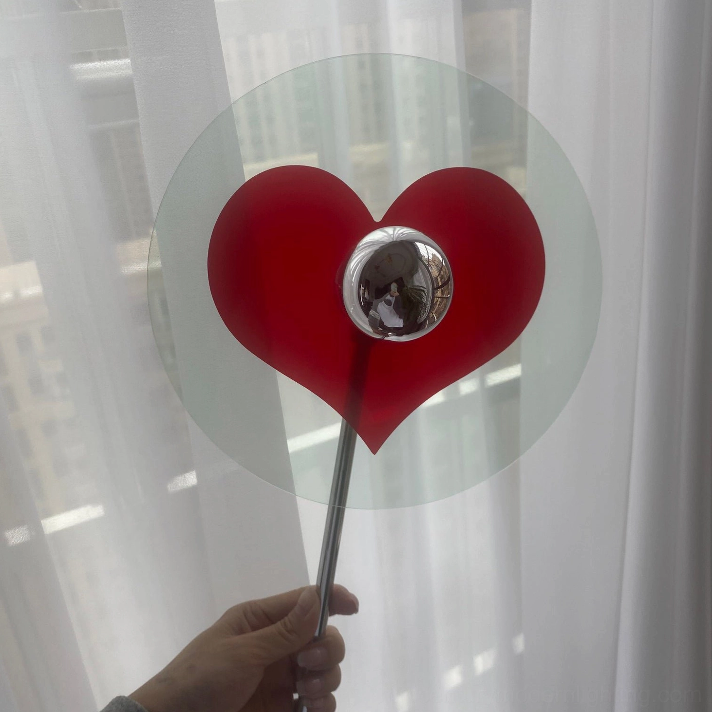 Close-up of handheld heart-shaped LED table lamp showing clear acrylic disc and chrome lamp head design