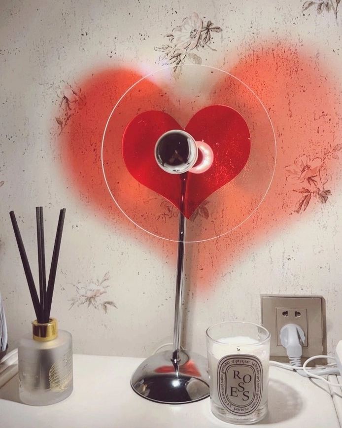 Heart-shaped table lamp casting warm heart shadow on wall, romantic bedroom lighting solution