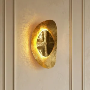 Helios brass sconce installed on luxury paneled wall showing warm ambient glow and curved sculptural form in modern bedroom setting