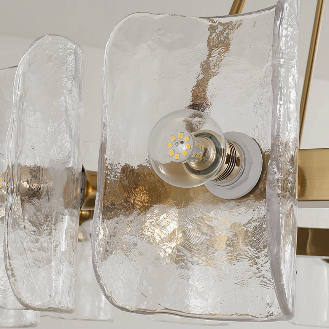 Close-up detail of Helios chandelier component showing rippled glass shade and exposed LED bulb with brass copper base