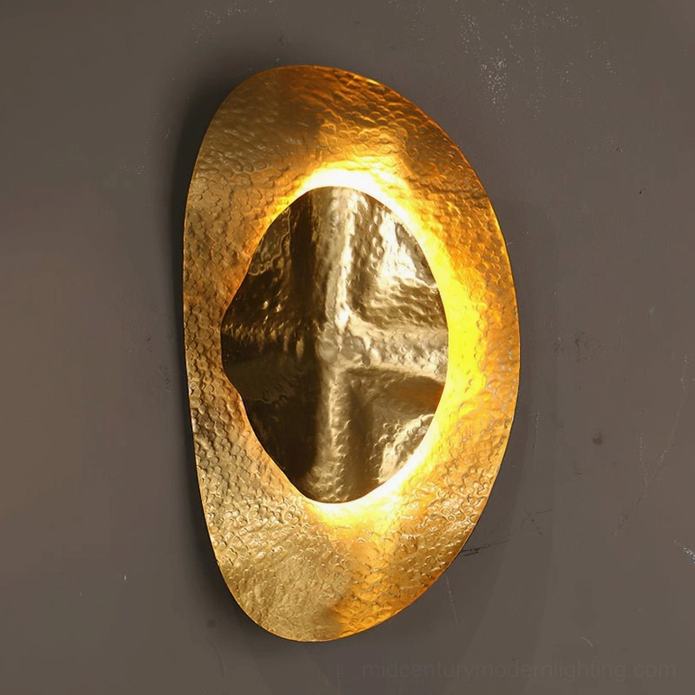 Helios hammered brass sconce in warm brass finish with organic oval form and artisanal hand-worked metalwork detail