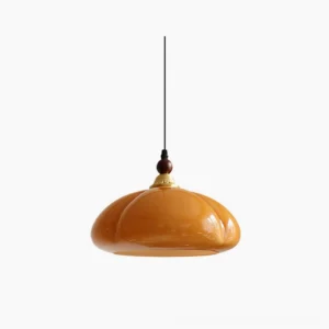 Herda pumpkin pendant light in caramel orange glass with walnut wood and brass top fixture, studio front view