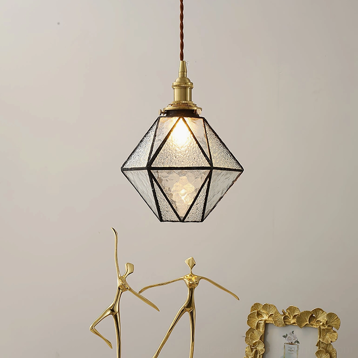 Hiro clear textured glass pendant lamp with black metal framing, close-up frontal view against gray studio wall with warm decor accents