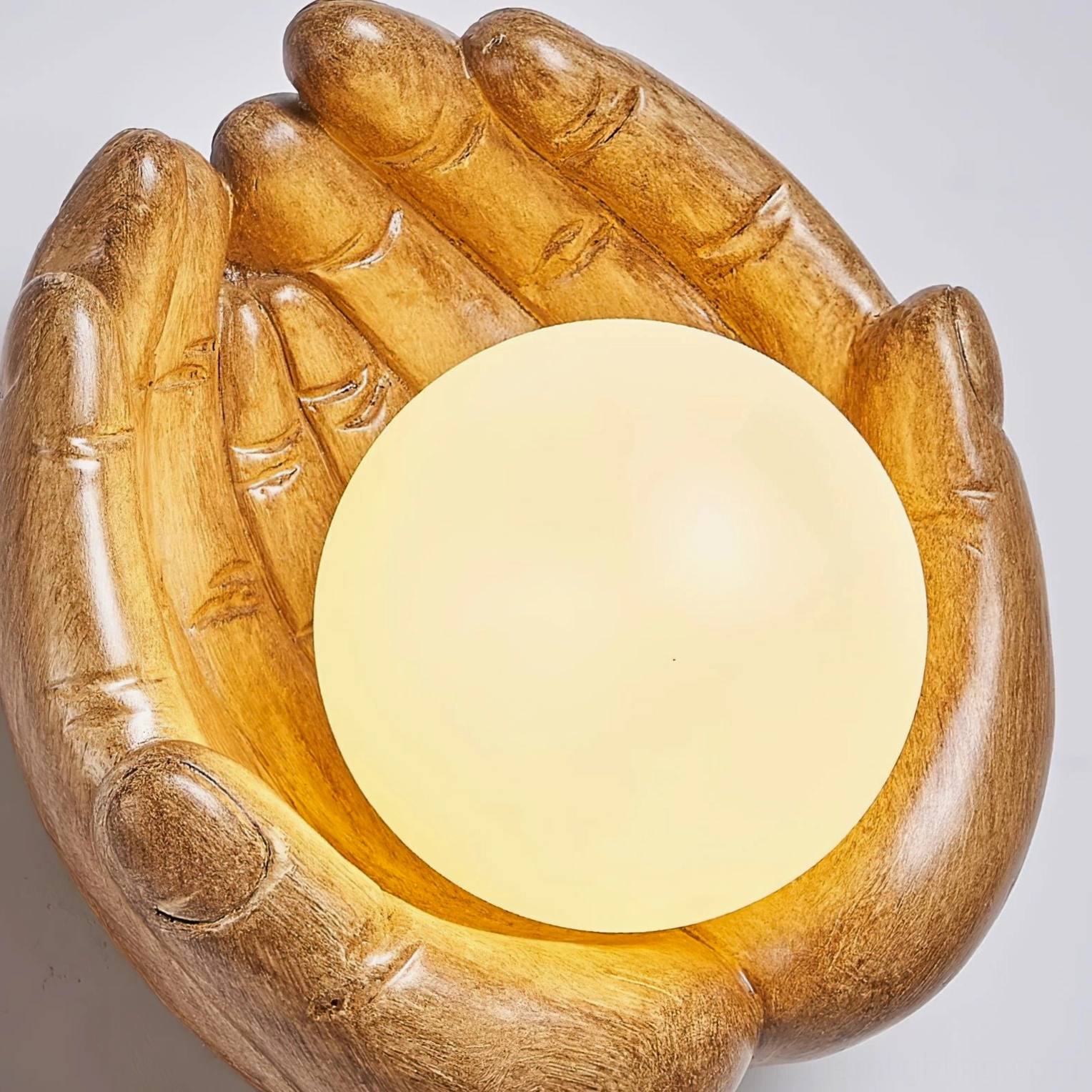 Extreme close-up detail of hand-sculpted resin wall lamp showing wood grain texture and anatomical hand craftsmanship