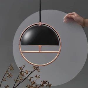 Close-up side angle detail of black dome pendant light with rose gold hardware and hanging black cord