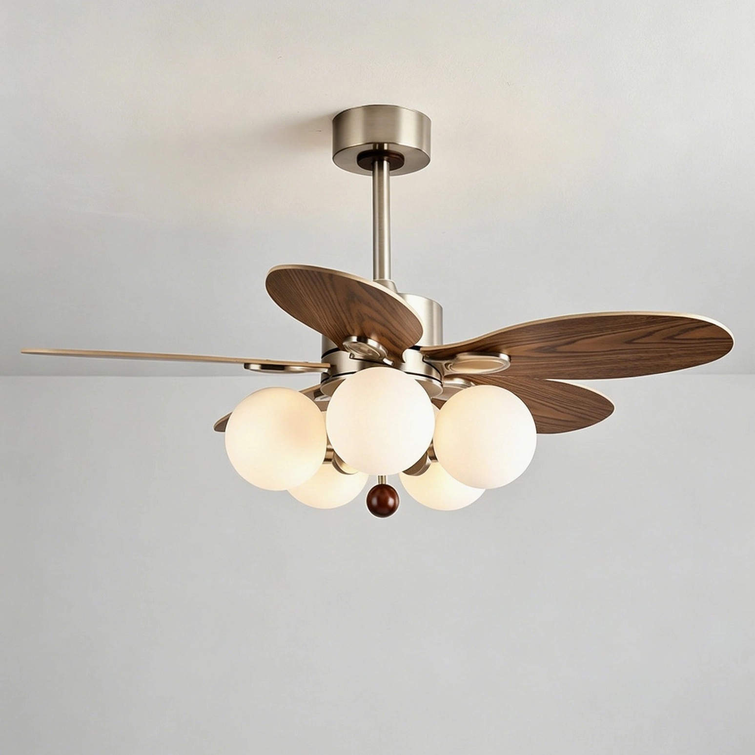 Studio photography of modern ceiling fan light featuring illuminated frosted glass globes creating soft diffused light, walnut wood core with chrome accents