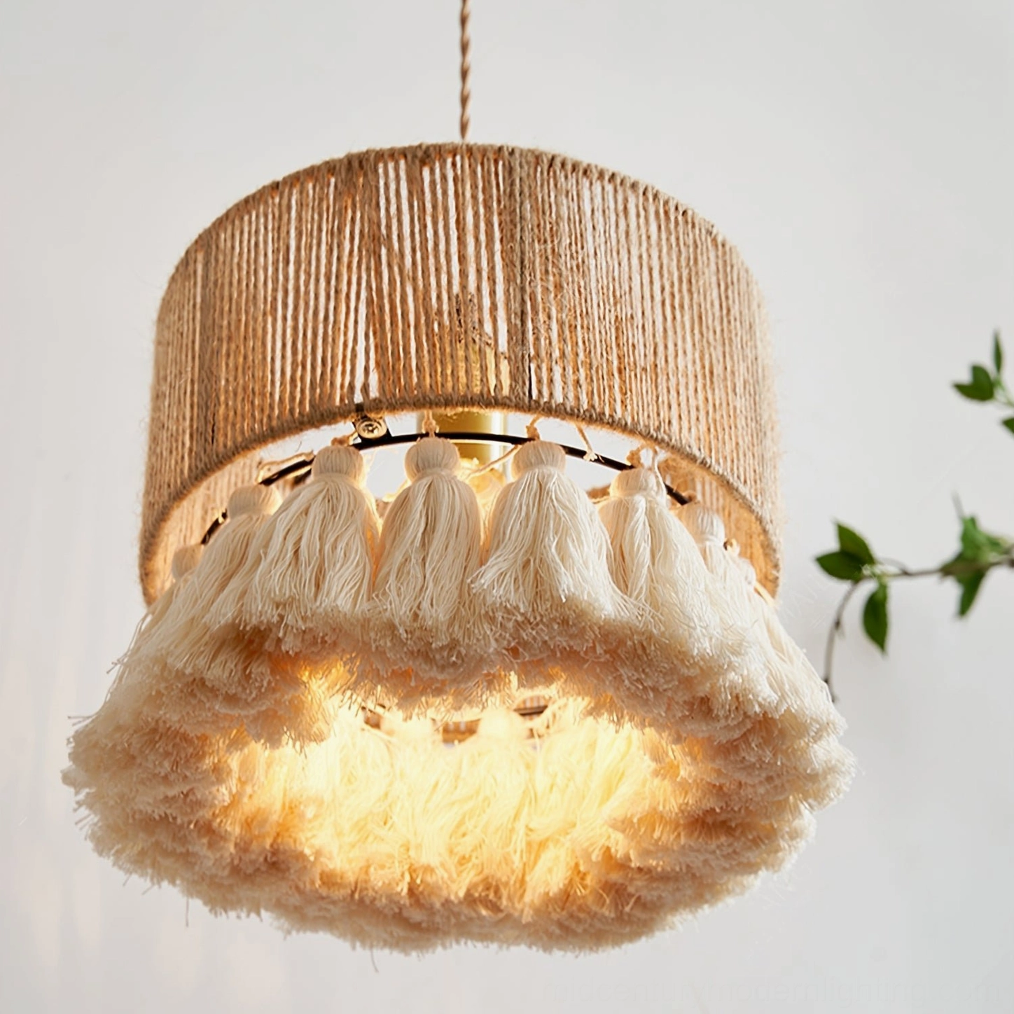 Illuminated Boho Rara tassel pendant lamp emitting warm soft light, close-up of thick fluffy cotton tassels with foliage backdrop