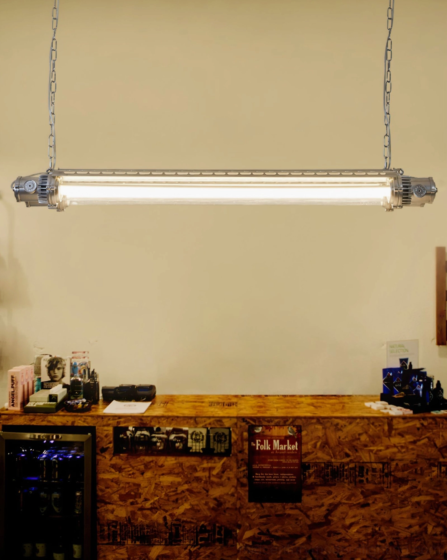 Industrial silver tube pendant light above wooden bar counter, warm ambient cafe atmosphere