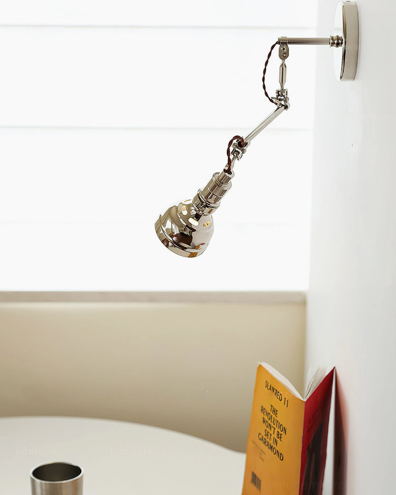 Side view of swing arm wall fixture in dining booth interior, exposed wiring and vintage industrial style