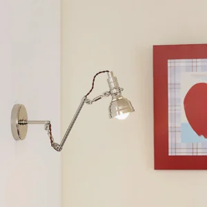 Vintage industrial swing arm wall lamp mounted in contemporary interior with artwork, polished chrome finish