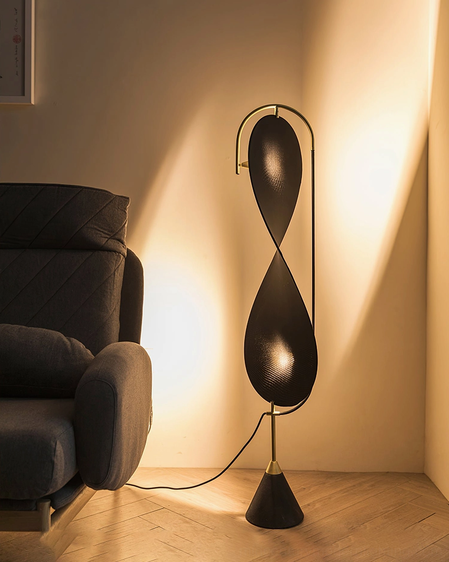 Infinite Floor Lamp at eye level in warm residential interior, showing black and gold finish casting soft ambient wall light