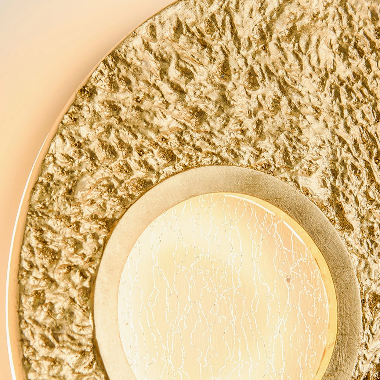Extreme close-up of gold Infinity wall lamp showing ultra-fine rough texture and frosted inner light panel