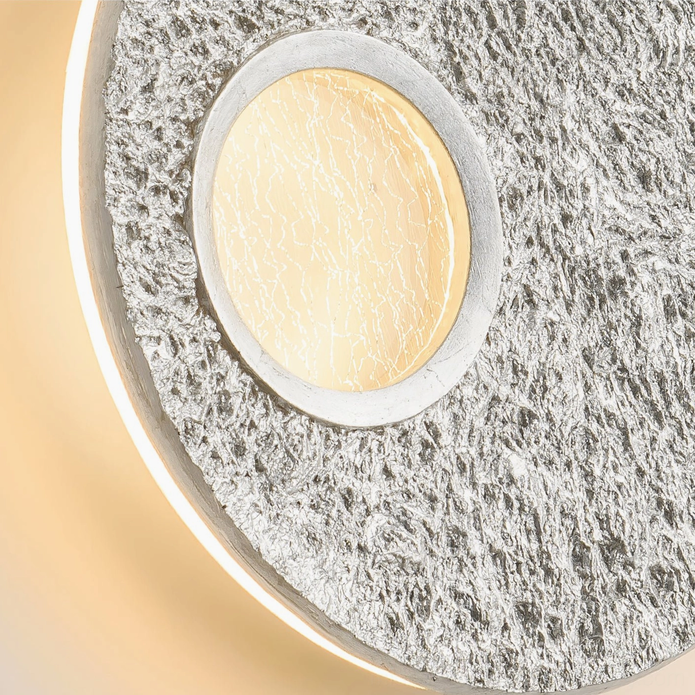 Close-up side view of silver Infinity wall lamp showing rough stone-like texture with backlit glowing inner ring