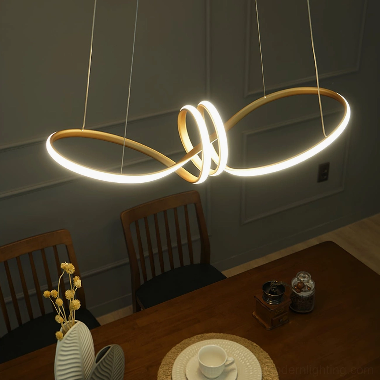 Infinity twist double loop gold LED pendant light in casual wooden dining room, modern minimalist chandelier with warm white glow