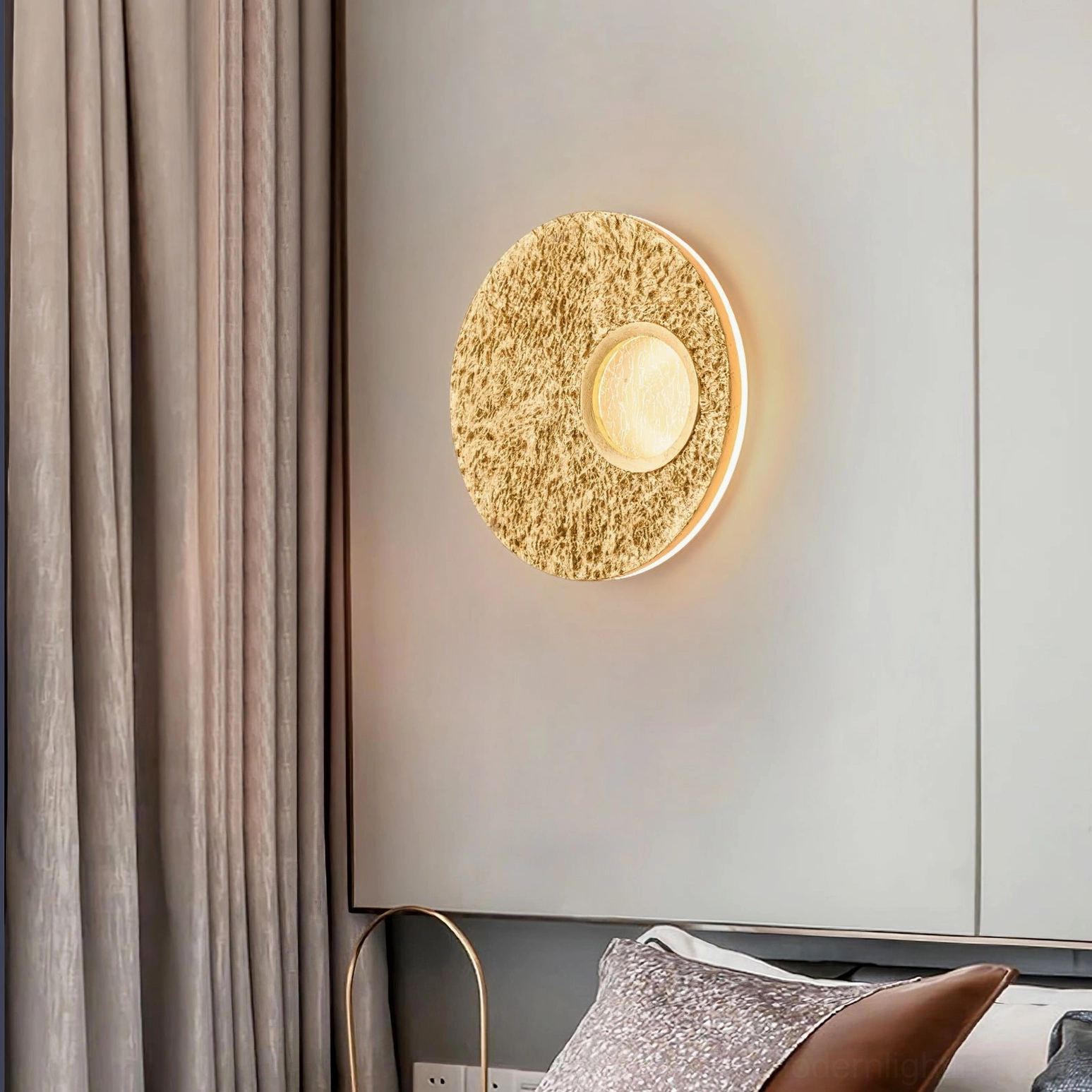Gold Infinity wall light fixture mounted in modern bedroom with warm ambient glow and side angle perspective