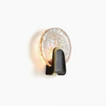 Ingot round rippled glass wall lamp with black brass trim, front studio view showing hammered texture detail
