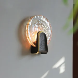 Ingot wall sconce mounted on grey wall with warm LED glow illuminating rippled glass surface