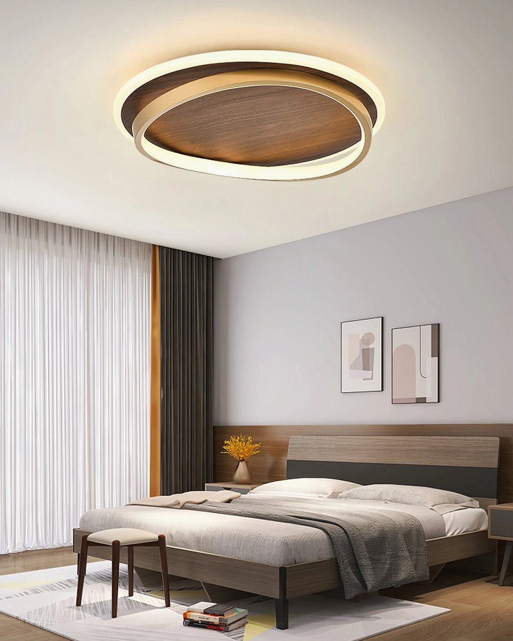 Integrated dual-ring LED ceiling fixture above bed with wall artwork, contemporary Scandinavian lighting aesthetic