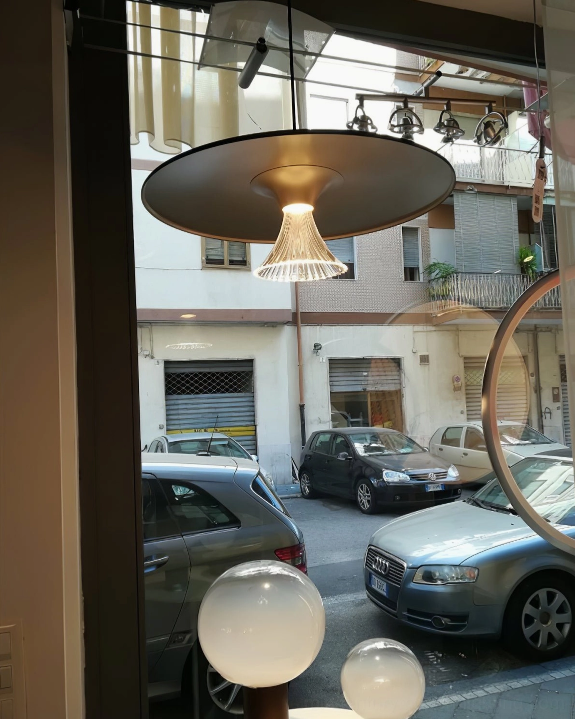 Ipho pendant light with bronze-black exterior and gold interior fluted glass shade, outdoor urban storefront