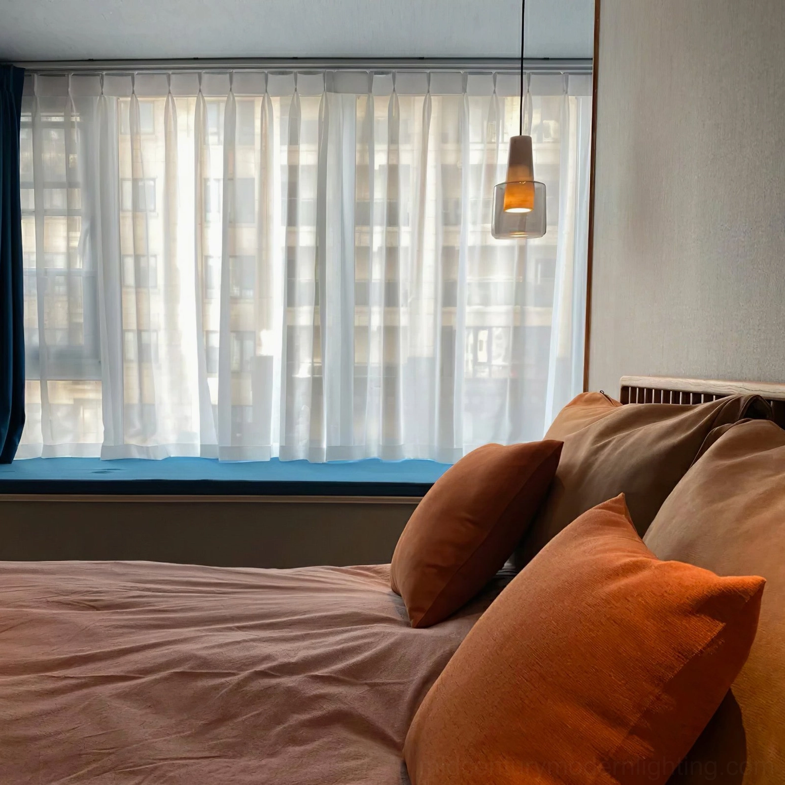 Issa pendant lamp suspended above bedroom window with sheer curtains warm cozy lighting