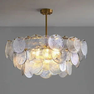 Overhead view of Jacobella glass disc chandelier with layered ripple textures and brass-gold suspension rod, neutral grey interior setting