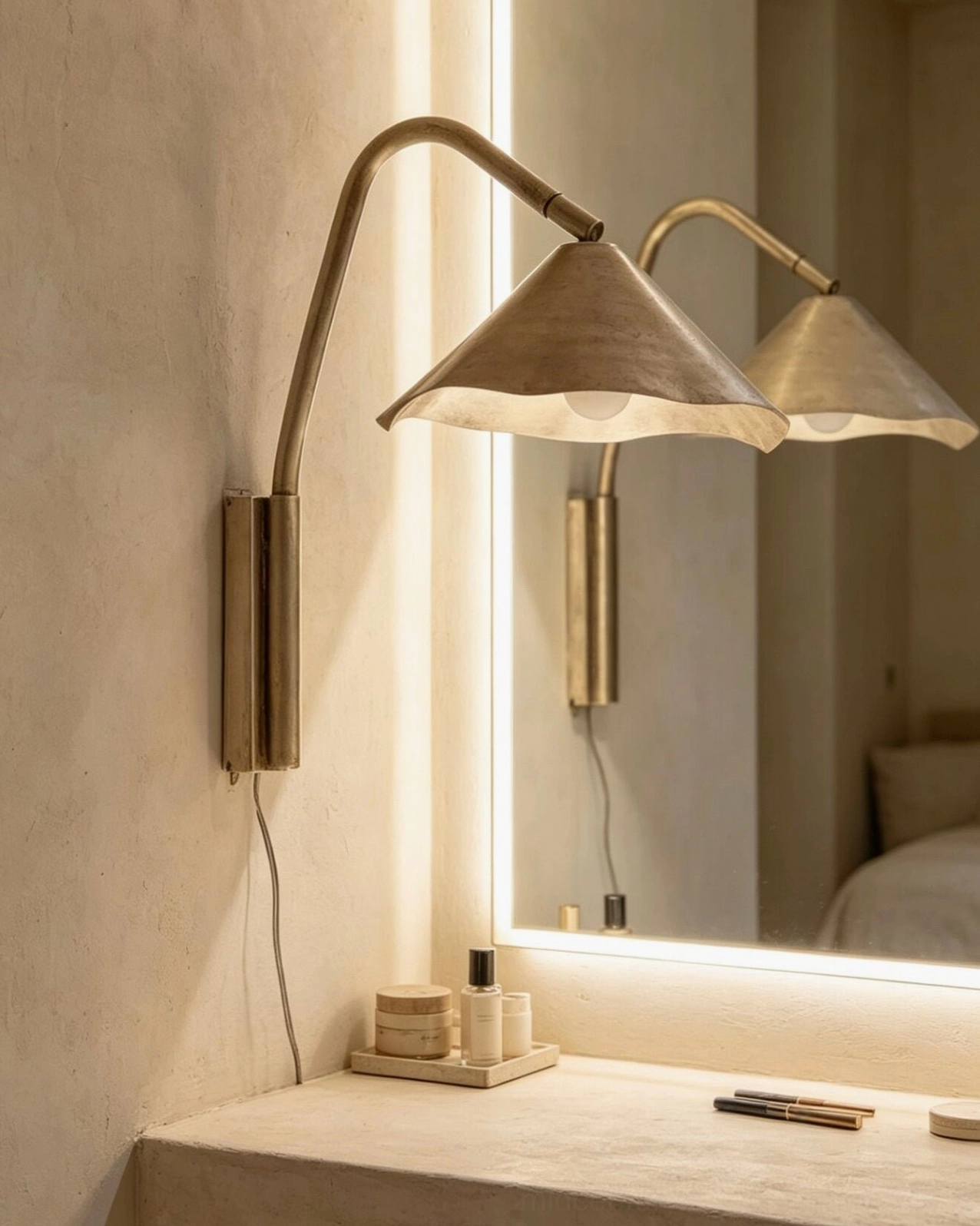 Pair of Janna scalloped wall sconces in brushed brass flanking vanity mirror in makeup room