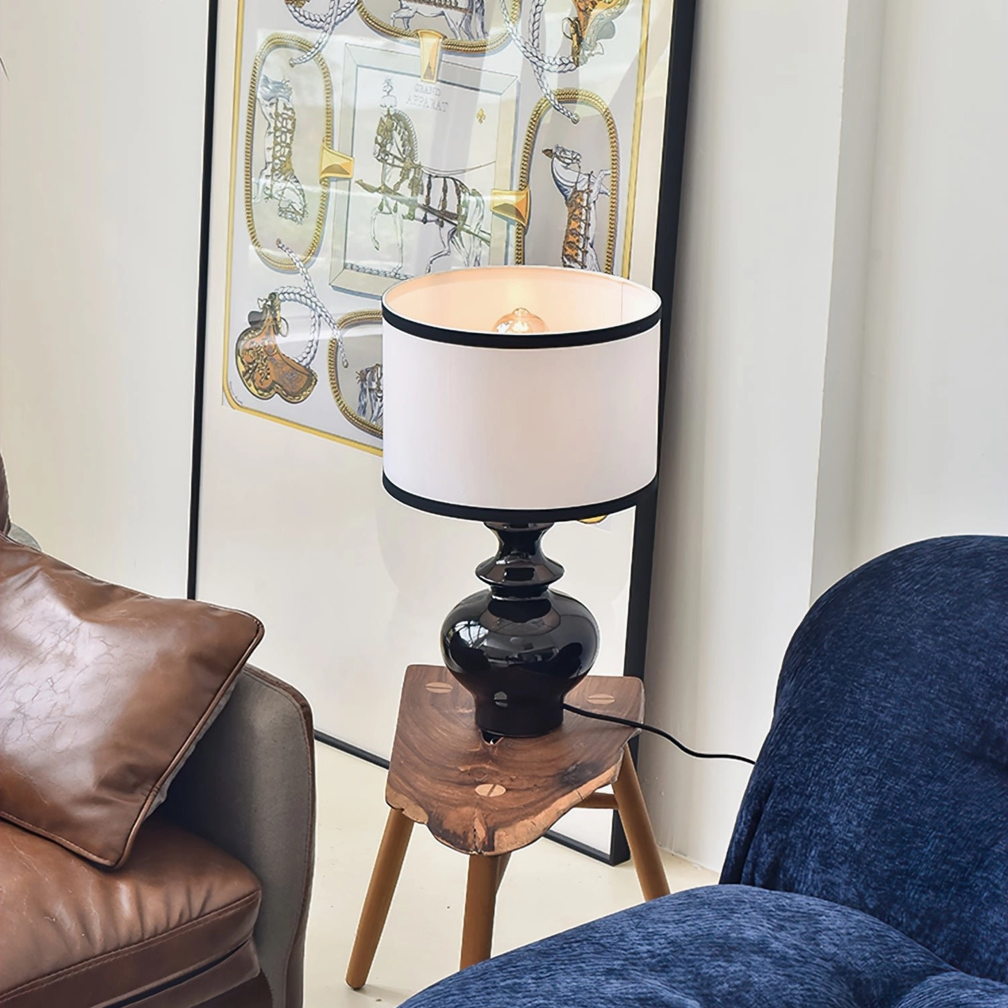 Ceramic Jarrige table lamp placed on wooden stool, eye-level view in sophisticated living room with leather and fabric seating