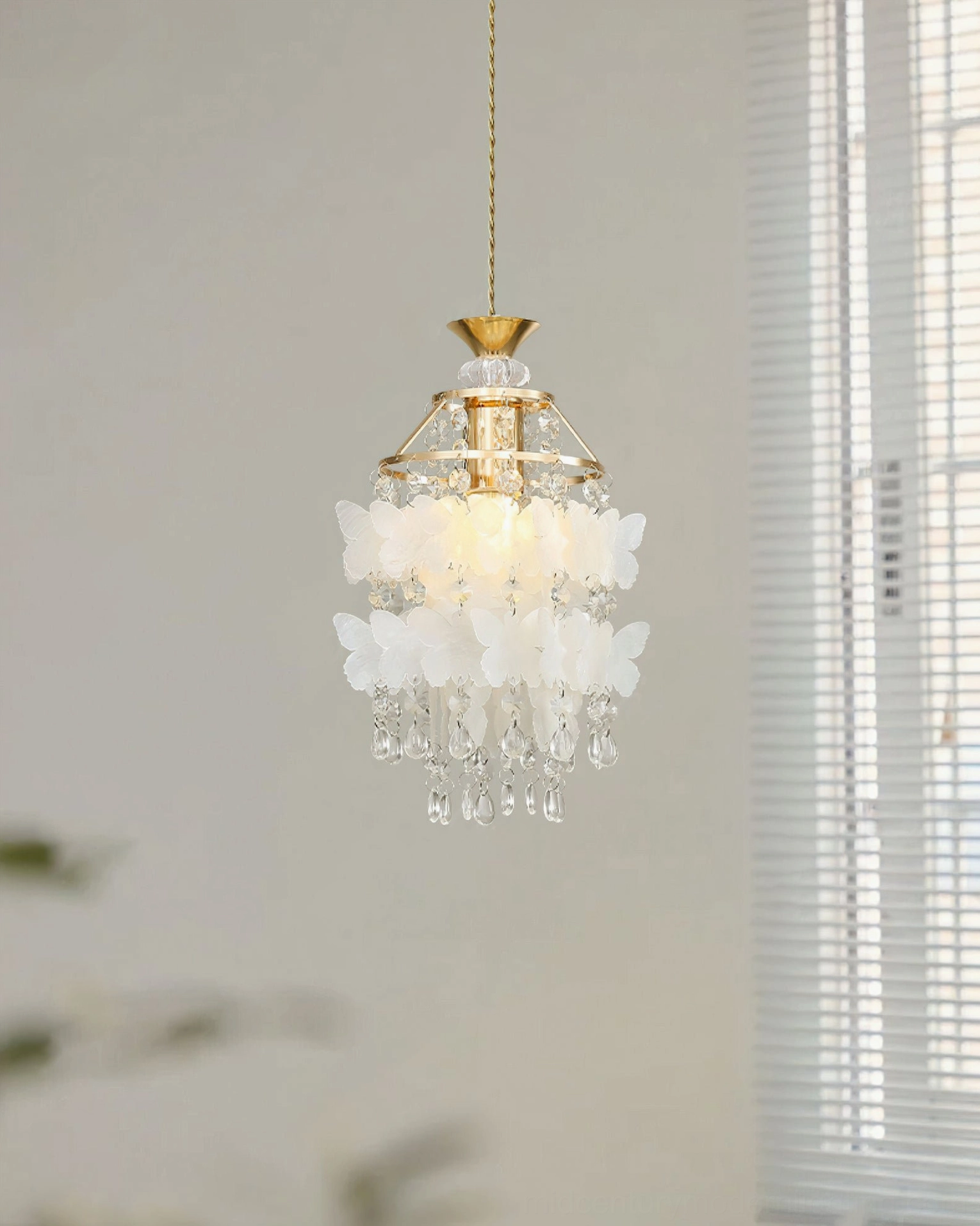 Mini Jasinski butterfly crystal pendant light in gold brushed brass finish, compact design view with warm indoor window background
