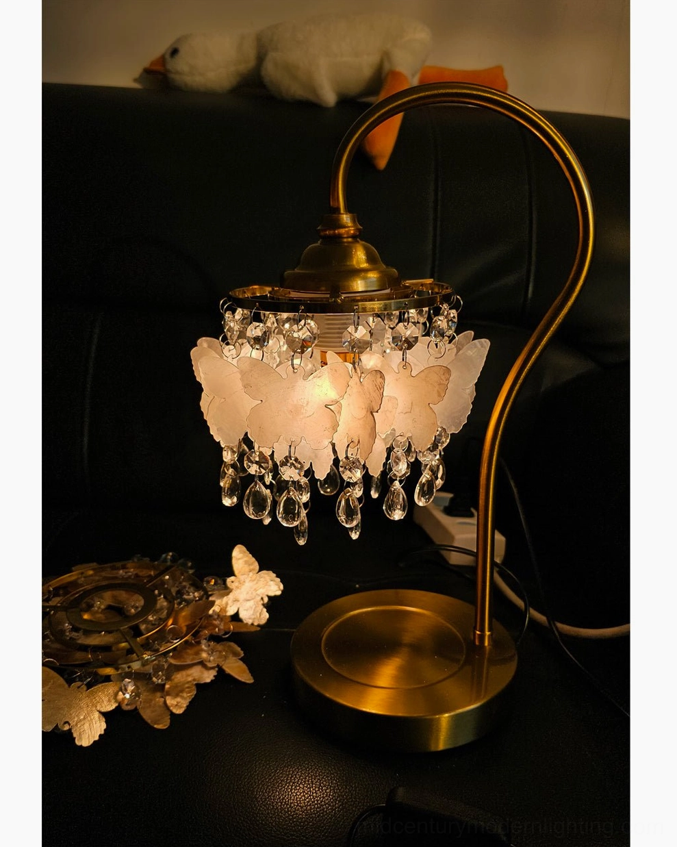 Overhead top-down view of illuminated Jasinski crystal butterfly lamp with additional butterfly décor and warm light effects