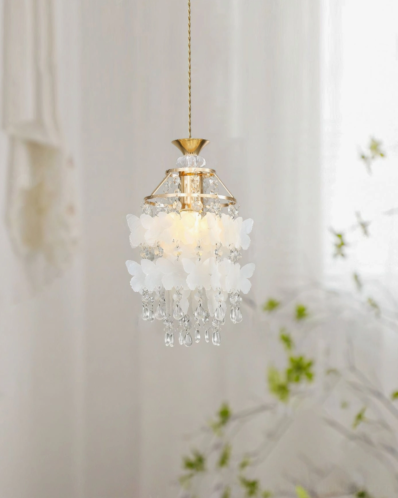 Jasinski crystal pendant light suspended in contemporary home setting with potted plants and natural window lighting, warm ambient style
