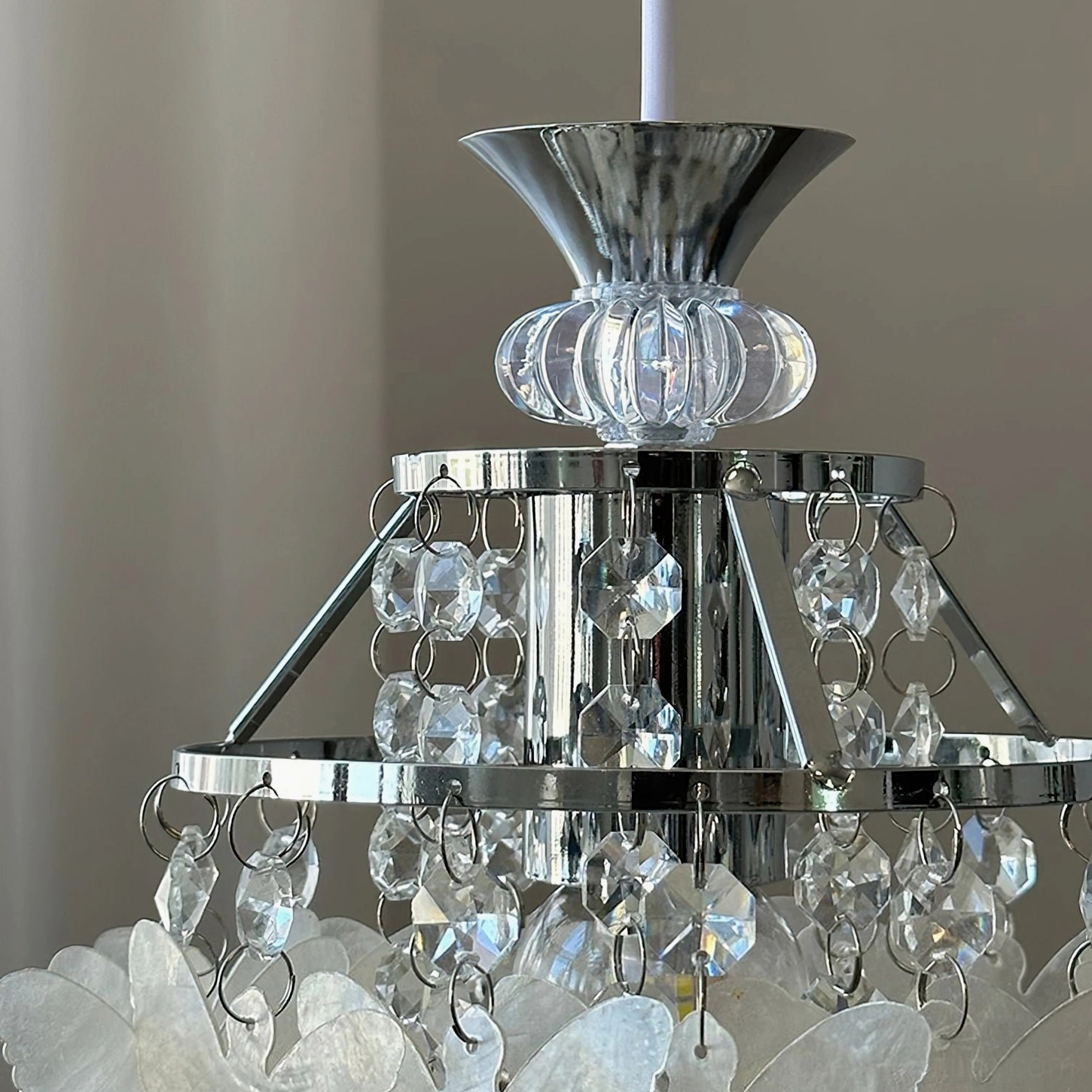 Low-angle close-up of Jasinski pendant metal frame structure showing polished chrome finish, crystal bead chains and ceiling mounting base