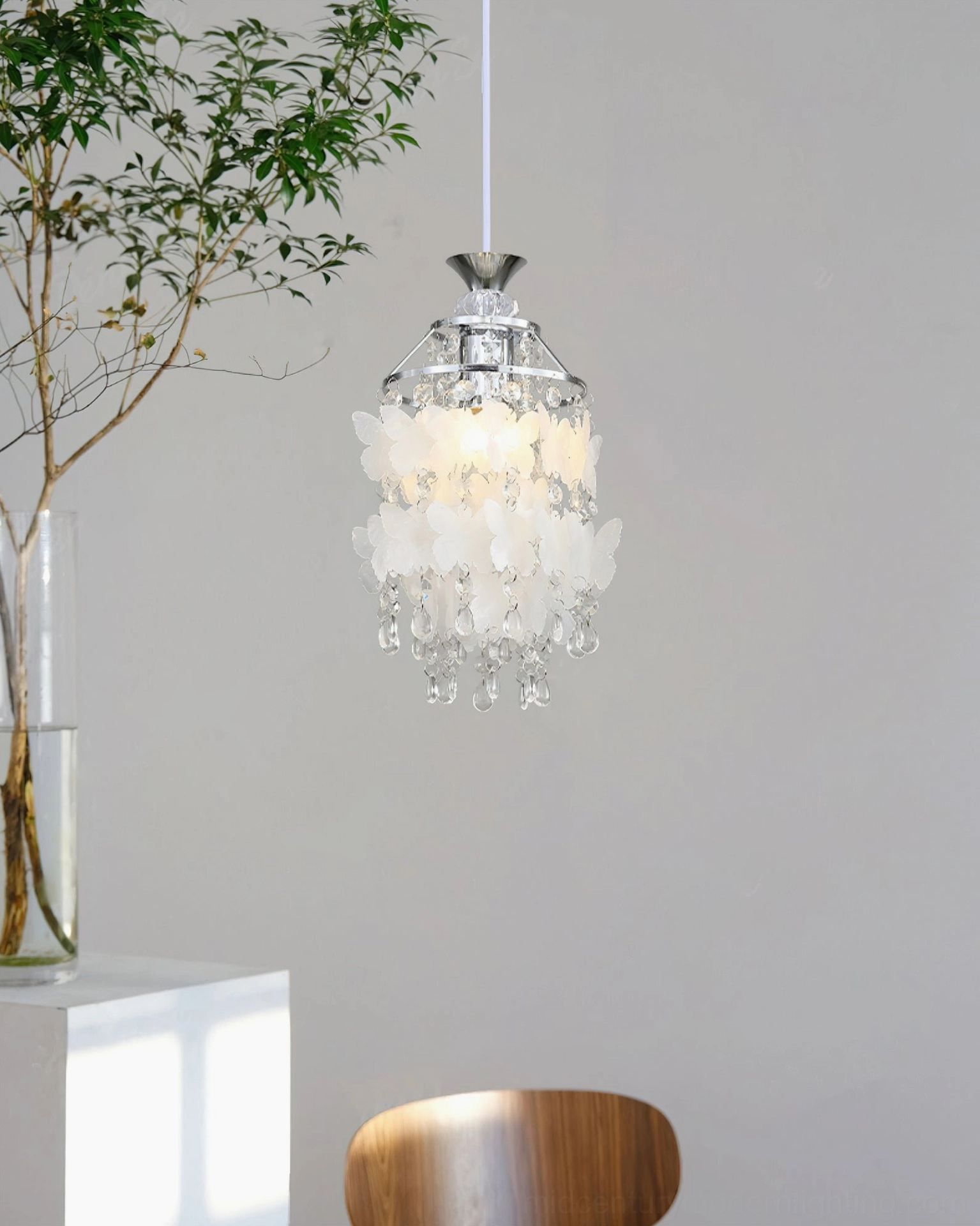 Jasinski butterfly crystal pendant light in mixed chrome and brass finish hanging in minimalist modern home with decorative chair and potted plant