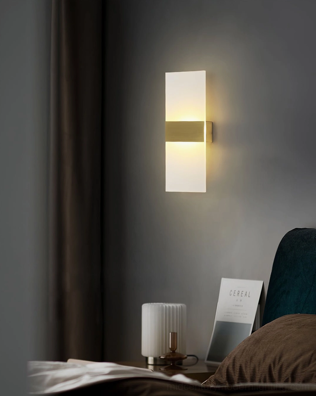 Compact minimalist wall sconce with brass strip and soft warm LED glow on bedroom nightstand