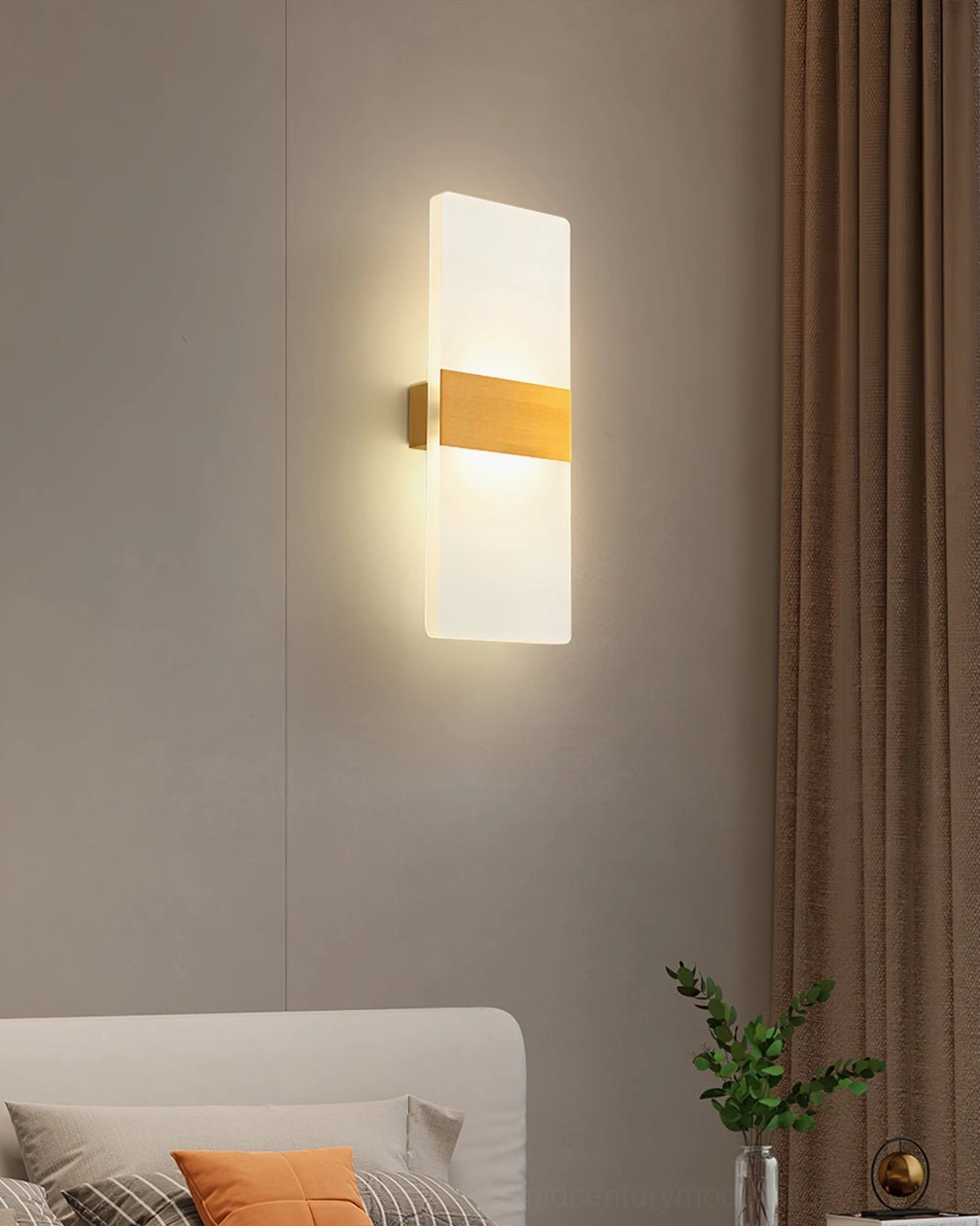 Up-down LED wall lamp with brass middle piece and frosted acrylic panels in bedroom setting