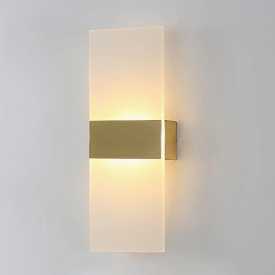 Vertical minimalist wall sconce with brass accent strip and warm glowing LED light on gray wall