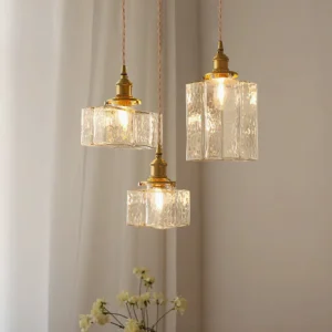 Three jewel brass pendant lights clustered above living room seating area with sheer curtains and minimalist interior design