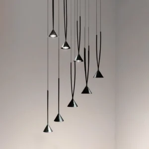 Asymmetric multi-head conical pendant lights suspended at varied heights in minimalist modern interior with gray gradient wall