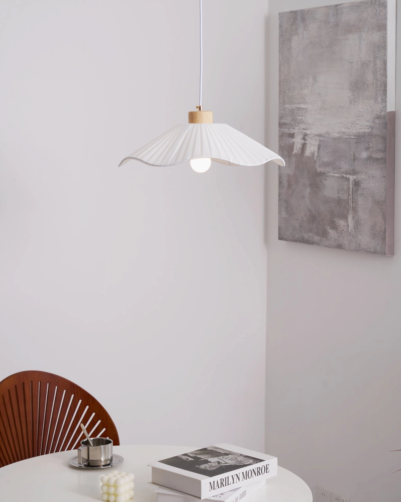 Jimi fabric pendant light low angle view above minimalist dining setup with books and decorative tableware, warm diffused lighting