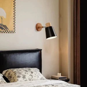 Joan Nordic wall lamp installed in modern bedroom above leather bed, creating focused reading light and minimalist ambiance