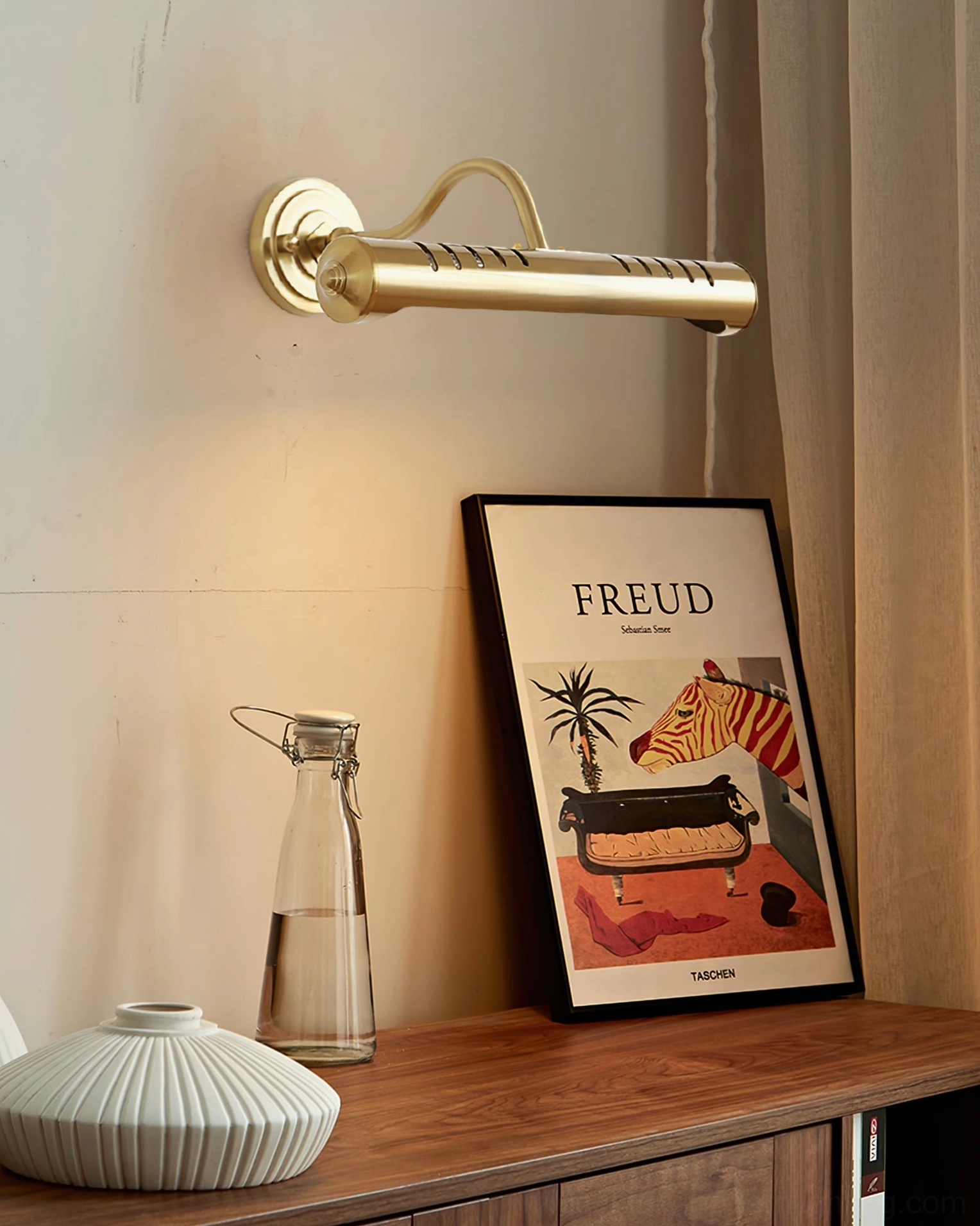 Joely gold brass wall lamp in living room setting creating warm ambient lighting on sideboard