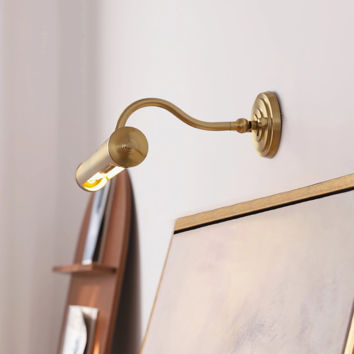 Joely gooseneck picture wall lamp mounted beside framed painting and bookshelf display