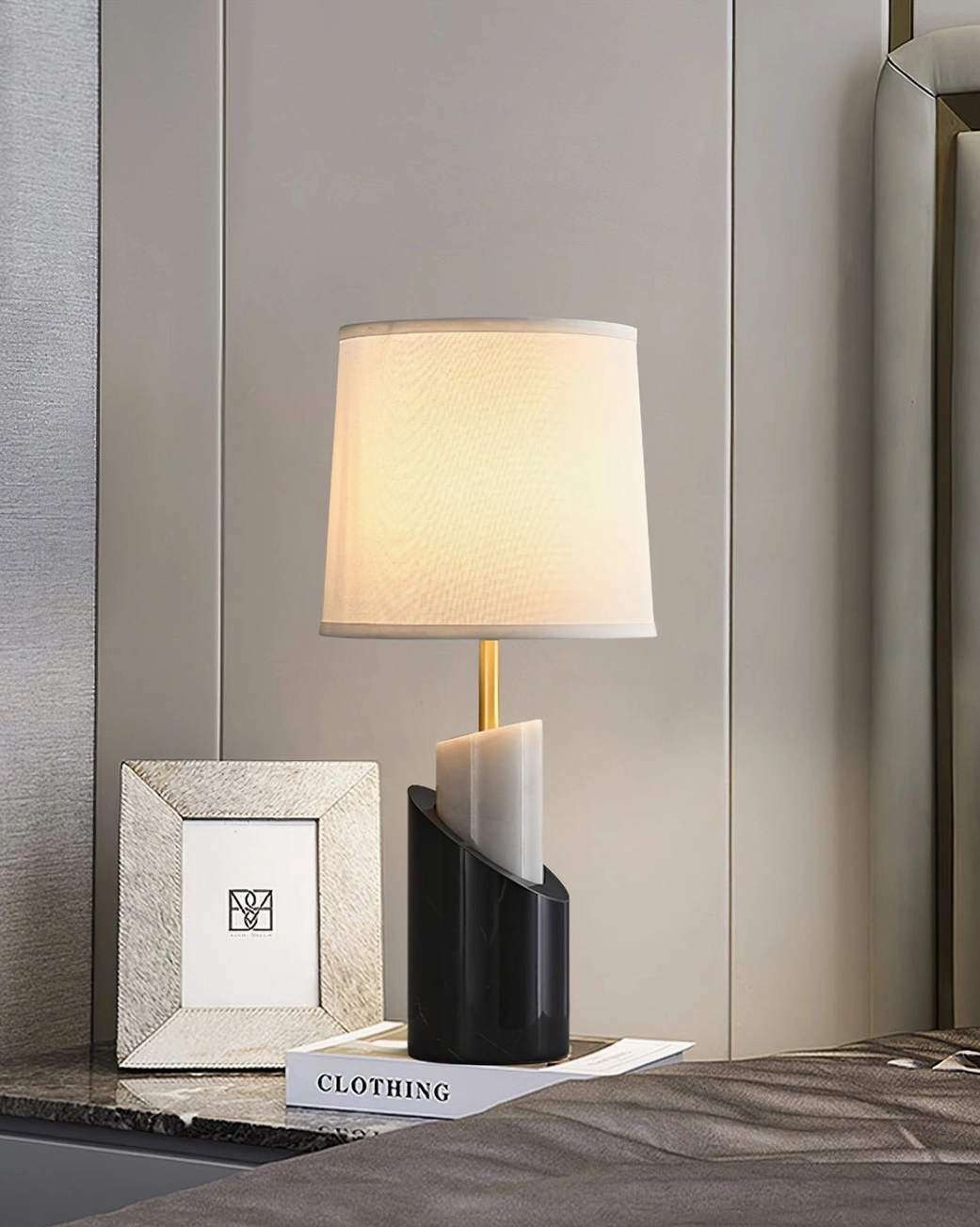 Jude table lamp on bedside marble surface with decorative frame and styling book