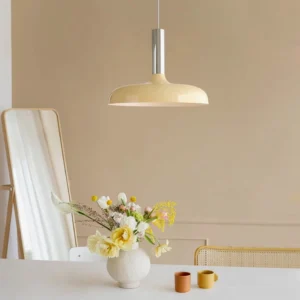 Julia modern pendant lamp cream shade with silver metal fixture displayed above dining table, low-angle view emphasizing sculptural geometry