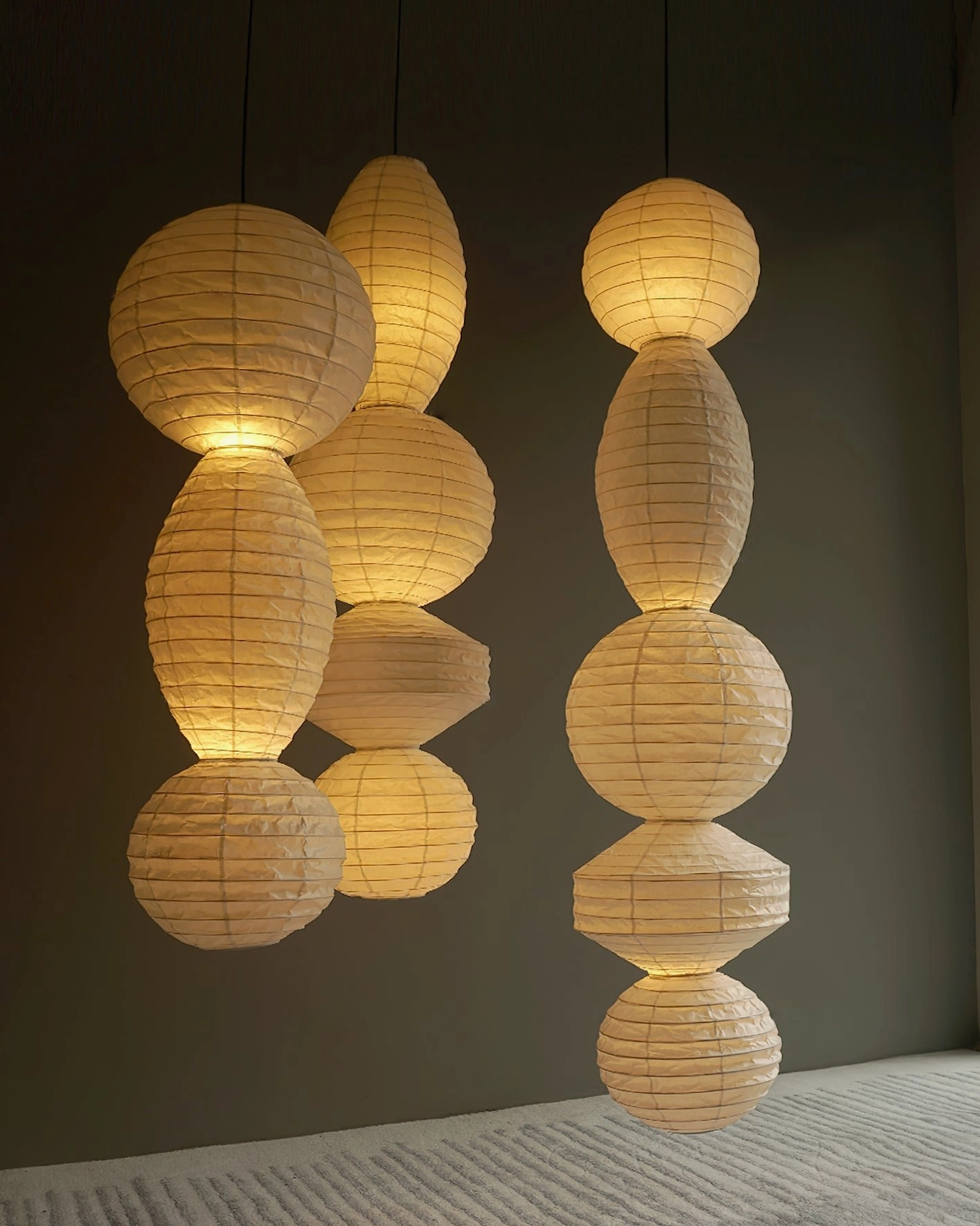 Two sets juni stacked paper lanterns dark wall paired asymmetrical warm tone design