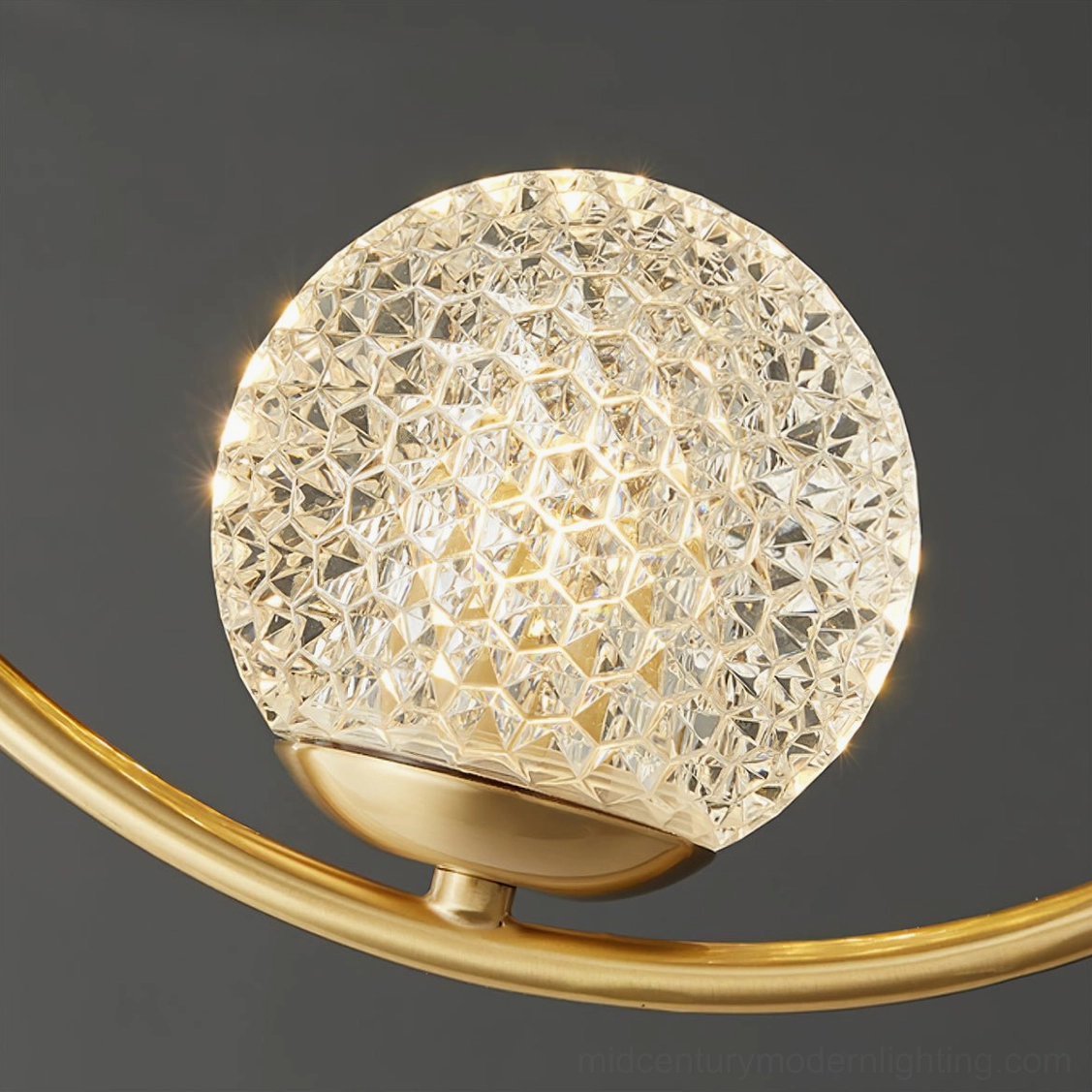 Close-up macro view of Jupiter's faceted clear glass shade with gold brass metal mount, highlighting textured geometric details