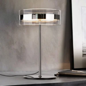 Modern cylindrical table lamp in home office desk setting, three-quarter perspective with warm LED light