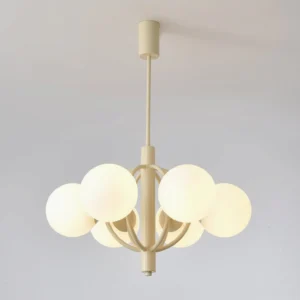 Kaiser chandelier illuminated, showing warm glow through frosted glass shades and cream metal arms